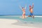 Couple Jumping On Beach Wearing Santa Hats