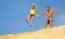 couple jumping off sand dune