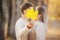 Couple kisses and closes with maple yellow leaf in autumn park, romantic happy date. Concept of love, relationship