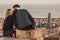 A couple is kissing in front of the views of Barcelona, Spain. It is sunset time