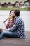 Couple kissing and sitting on pier, girl holding yellow flowers