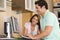 Couple in kitchen with computer and coffee smiling