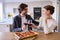 Couple In Kitchen At Home Eating Homemade Pizza Drinking Wine Sitting At Counter