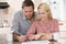 Couple in kitchen with newspaper with coffee