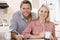 Couple in kitchen with newspaper with coffee