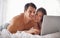 Couple with laptop, streaming movie and relax at home with technology, happy and fun together with film website Love