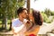 couple of latin lovers leaning on a wooden poster form a heart with their hands and kiss each other. They are very happy and in