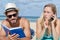 Couple layed on beach man readying book woman on cellphone