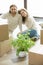 Couple looking at camera sitting on floor with boxes, vertical