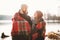 Couple looking each other near winter lake under plaid