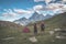 Couple looking at the majestic view of glowing mountain peaks at sunset high up on the Alps. Rear view with camping tent, focus i