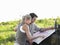 Couple Looking At Map On Jeep Bonnet At Landscape