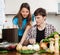 Couple looking notebook during cooking vegetables