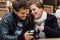 Couple Looking At Photographs On Camera At Restaurant