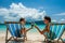 Couple in loungers clinking their glasses on a tropical beach