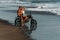 A couple in love on the beach meets the sunset. Beautiful couple on a motorbike meets sunset by the sea. Couple on a bike