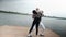 The couple in love dance social dance bachata pier on the lake, town horizon