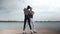 The couple in love dance social dance bachata pier on the lake, town horizon