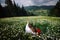 Couple in love is enjoying the landscape view of the charming sunny mountains while sitting on the blooming chamomile