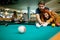 Couple in love enjoying playing billiard in bar