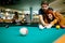 Couple in love enjoying playing billiard in bar