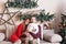 Couple in love on a gray sofa next to Christmas tree and presents, playing with puppies Husky Eskimo dog.