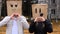 Couple in love having fun by cover head with paper bags making loving hearts gestures