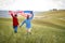 A couple in love having good time running through a meadow with unfurled American flag above heads. Election, campaign, freedom