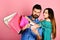 Couple in love holds shopping bags on pink background.