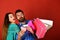 Couple in love holds shopping bags on red background.