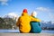 Couple in love hugging together with colorful cloths sitting and relaxing on a wooden pier on a clear sky sunny winter day view fr