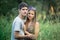 Couple in love hugs while standing among the grasses in the summer at sunset