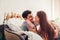 Couple in love kissing lying in bed in the morning. Man gives gift box to his girlfriend for Valentines day