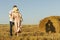 Couple in love kissing in a wheat field. Shadow of this young people falls on a hay bale.