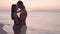 a couple in love, a man and a woman at dawn, stand on the ocean shore during a family vacation and kiss passionately