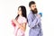 Couple in love in pajama, bathrobe stand back to back. Girl with dumbbell, man with coffee cup, isolated on white
