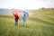 A couple in love running through a meadow with unfurled American flag holding by hands. Election, campaign, freedom concept