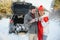 Couple in love sitting in car trunk drinking hot tea in snowy winter forest and chatting. People relaxing outdoors during road