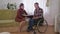Couple in love spends time together, young wife and her husband in wheelchair read interesting stories in room