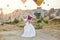 Couple in love stands on background of balloons in Cappadocia. Man and a woman on hill look at a large number of flying balloons