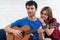 Couple in love. Stunning sensual portrait of young couple indoors. Attractive young man playing acoustic guitar for his