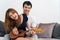 Couple in love. Stunning sensual portrait of young couple indoors. Attractive young man playing ukulele for his beloved