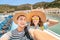 Couple in love taking selfie on a deck of a sea cruise ship wearing hats. Vacation and travel concept