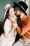 A couple in love in trendy clothes and hats are sitting on a brown sofa, embracing in a spacious beautiful Studio. family concept