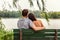 Couple in love - Two young lovers sitting together on a park bench looking at view of romantic lake. Beijing summer