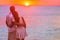 Couple in love watching sunset together on beach travel summer holidays. People silhouette from behing standing enjoying