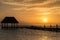 Couple in love at a wooden pier palapa enjoying Sunset at Holbox island near Cancun, Traveling Riviera Maya. Mexico adventure.