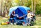 Couple of lover are camping near the forest have relaxing activity with man play guitar and woman give him with a cup of coffee