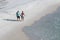 A couple of lovers walk down the beach enjoying the surf and the sun during fall and winter months