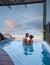 Couple in luxury villa enjoying in the plunge pool looking out over ocean and beach during sunset